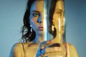 Beauty portrait of a woman with a large glass near her face. Distortion and refraction of reflection