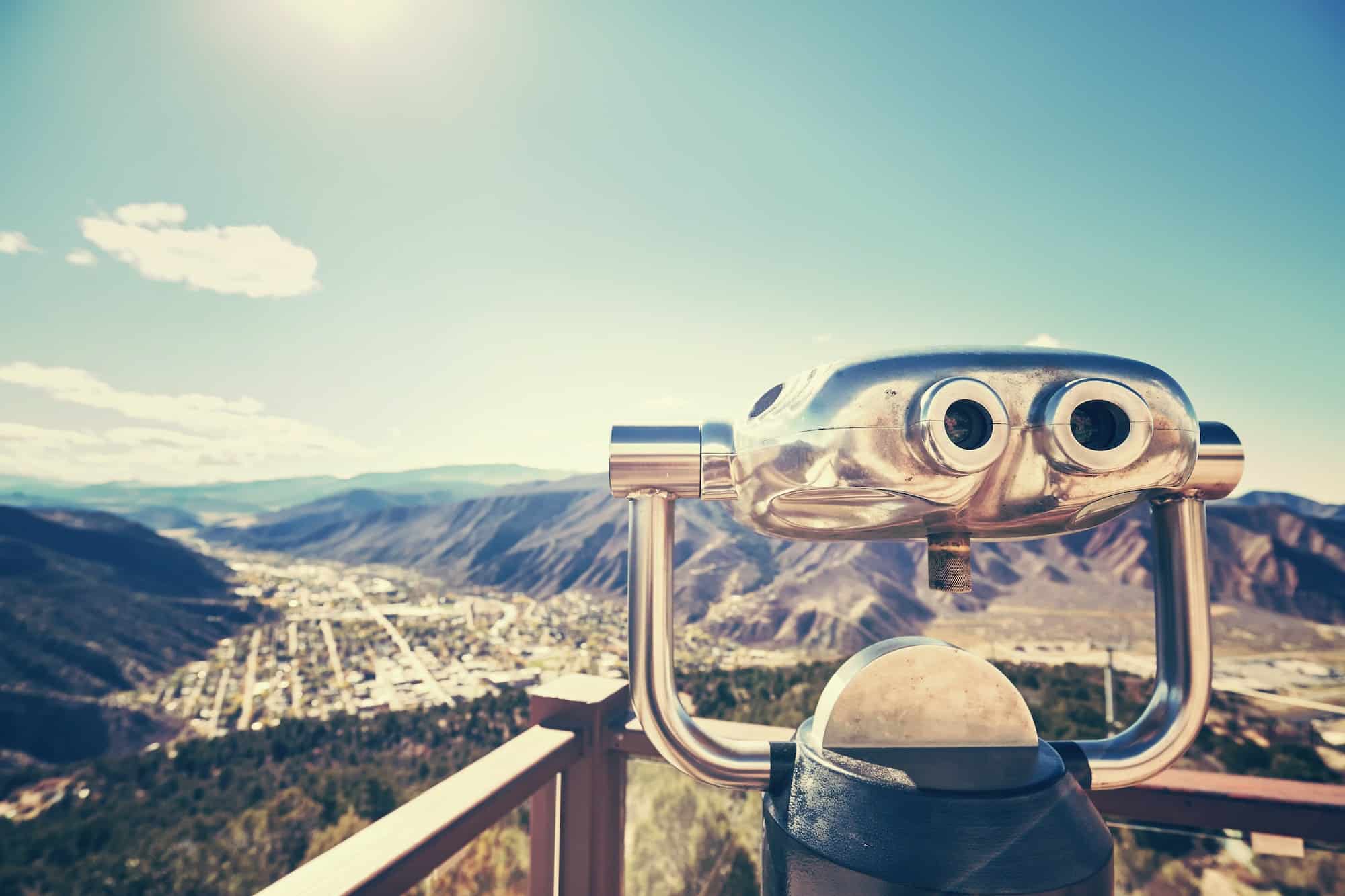 Color toned photo of binoculars looking out over a valley.