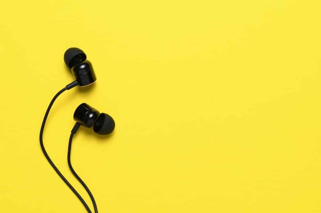 Earbuds on yellow background with text space
