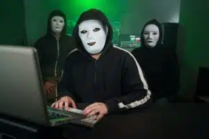 Team of Masked Hackers Using Computer to inflict Data Breach Attack on Government Servers