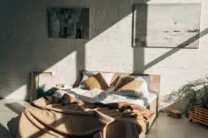 bedroom interior with bed, pillows and paintings in sunlight with shadows