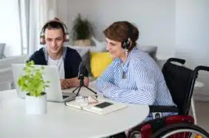 Disabled people sitting at the table indoors at home, recording podcast at home