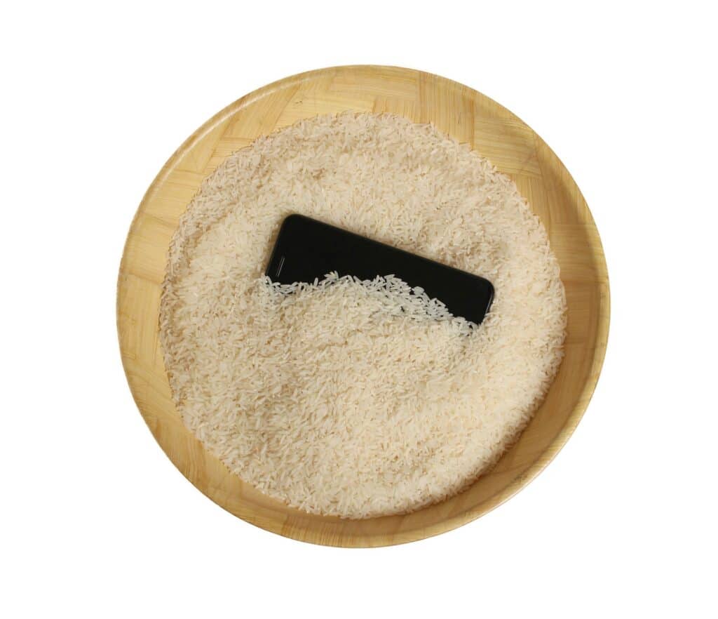 Apple rät allen, ihre Telefone nicht mehr in Reis zu legen. Smartphone in einer Schüssel mit weißem Reis, um Wasser aus dem Telefon zu entfernen